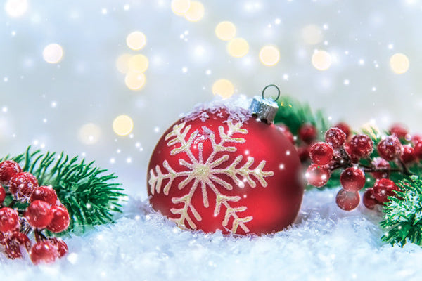 Red Christmas ball with snowflake design on a snowy background with lights