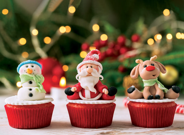 Three cupcakes with Santa Claus, snowman, and reindeer decorations against a festive background.