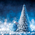 Blue Christmas ornament and miniature tree against a blurred blue background