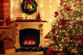 A cozy Christmas living room scene with a decorated evergreen tree on the right, a lit fireplace with festive mantel decorations on the left, and warm string lights throughout the room.