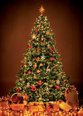 Decorated Christmas tree with lights and ornaments against a brown background