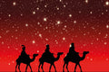 Silhouettes of three wise men on camels against a red night sky with stars.