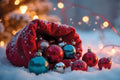 Red sack filled with colorful Christmas ornaments in a snowy setting with blurred lights in the background.
