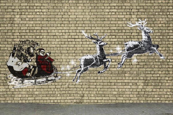 Street art of Santa Claus in a sleigh pulled by reindeer on a brick wall.