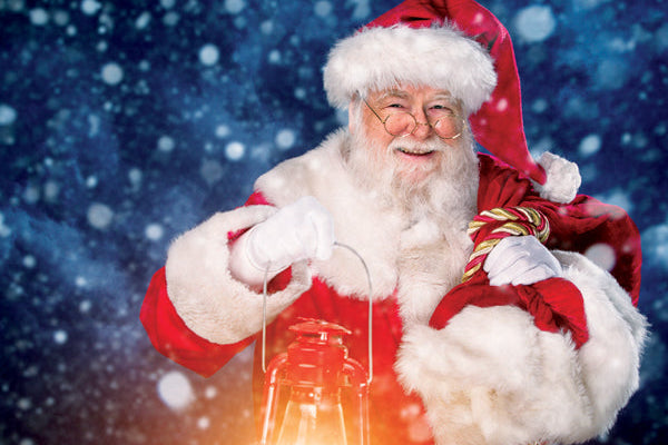 Santa Claus holding a glowing lantern against a snowy background